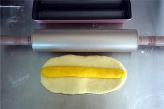 制作蛋白：将180克的白色面团擀开成21*10厘米的面片，将黄色棒状面团放在上面。