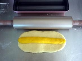 制作蛋白：将180克的白色面团擀开成21*10厘米的面片，将黄色棒状面团放在上面。