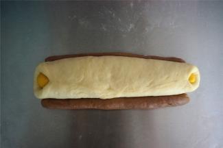 将粗细两条可可面团分别放在白色面团两旁，如图。