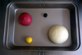 将5克的面团加入微量的深黑可可粉揉合，20克的面团加入南瓜粉揉合，130克的面团加入甜菜根粉揉合，剩下的白色面团揉圆。