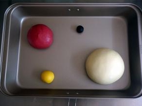 将5克的面团加入微量的深黑可可粉揉合，20克的面团加入南瓜粉揉合，130克的面团加入甜菜根粉揉合，剩下的白色面团揉圆。