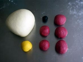 将发酵好的面团按压排气后分别揉圆，然后将红色面团分成2份20克的，3份30克的小面团，揉圆。用保鲜膜将面团盖好。