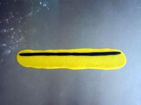 将黑色面团搓成21厘米的棒状。黄色面团擀开成21*3厘米的面片，包入黑色棒状面团，花朵的中心完成。