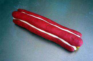 用红色的棒状面团围住黄色的花心面团，放的时候注意大小相隔，其中两个红色花瓣之间放入一条白色棒状面团，并用刮板稍微按压一下，这样更能突出花瓣的形状。