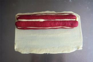 从白色面团中切取40克面团，擀成21*15厘米的面片，将花瓣整体包裹住，轻轻滚动搓平。