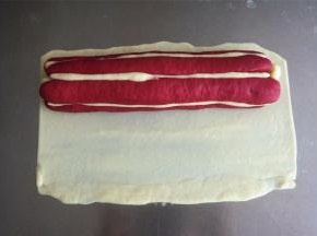 从白色面团中切取40克面团，擀成21*15厘米的面片，将花瓣整体包裹住，轻轻滚动搓平。