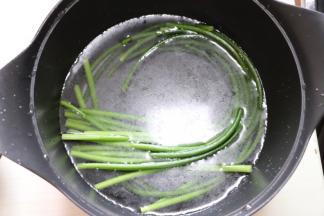 锅中水烧开放少许盐和几滴食用油（为了使蒜苔颜色更翠绿）放入蒜苔煮不到一分钟断生取出放冷水浸泡