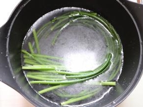 锅中水烧开放少许盐和几滴食用油（为了使蒜苔颜色更翠绿）放入蒜苔煮不到一分钟断生取出放冷水浸泡