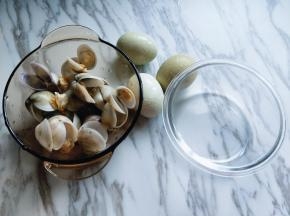 泡好的蛤蜊需要焯水，锅中加入清水，加入料酒，生姜烧开，加入蛤蜊，煮开口即可关火，捞出纯净水冲洗干净。