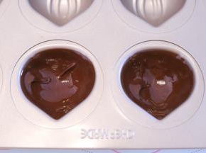分别倒少许巧克力液到学厨的板栗12连模内，轻晃至巧克力液粘满模具