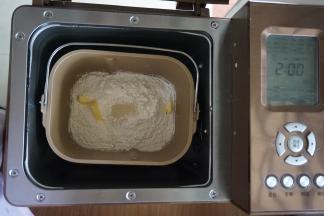 倒入奶粉和面粉，加入切成小块的黄油，在面粉顶端加入酵母，将面包桶放入到东菱1352AE-3C面包机里