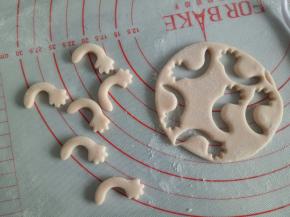 剩余淡粉色的面团揉一下，擀厚一点，大概2mm厚，用模具压出猪猪的胳膊来(没有模具可以先取2克面团揉成长条，稍微压扁，一头用刮板整成手掌状)