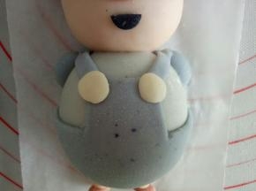 步骤19的背带也粘上，再取1克的白色面团，分开两份揉圆压扁，做扣子