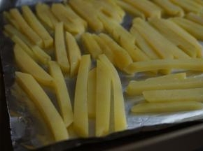 烤盘里垫一张锡纸，倒一点油在上面，把土豆条放上去，每一根都裹上油。不要重叠摆放，平铺着放（也可以将油倒入盆里，上面盖一张保鲜膜，摇晃几次，使土豆条都裹上油）