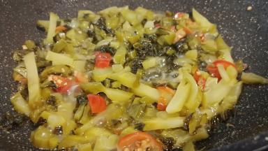 锅里留一点底油，下蒜泥炒香、再放酸菜、泡椒翻炒。