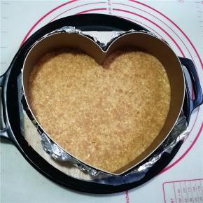 慕斯蛋糕圈底部用锡纸包裹住，放在烤盘中，将饼干碎倒入模具中，用勺子按压均匀后放入冰箱冷藏