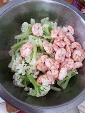 找一个凉拌盆，放入煮好的菜花跟虾仁，加盐，香油翻拌一下。