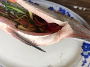 把一部分姜丝和葱段，装入鱼肚里