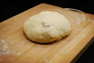 将发酵好的面团，排出空气，揉搓光滑的圆面团，盖上保鲜膜进行15分钟的中间发酵。