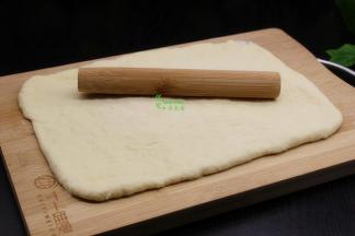 中间发酵好的面团在案板上撒点面粉，擀成长方形面片。