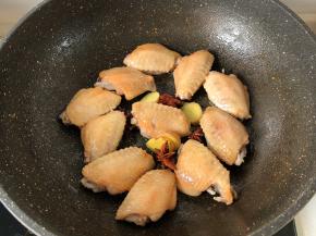 锅放油烧热放鸡翅煎两面微黄，加八角和姜片