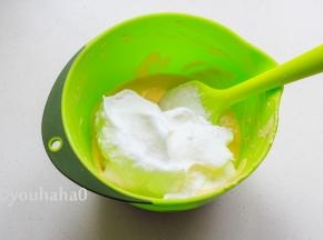 取1/3蛋白霜放入蛋黄糊中，用刮刀上下翻拌均匀，勿画圈搅拌，易消泡。