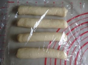 从上往下卷起，卷成长条状，盖上保鲜膜，松驰5-10分钟