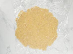 用手抓握成团，并放在两张保鲜膜中间，用擀面杖擀成比派盘大一些的圆形面皮。