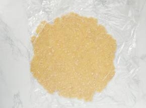 用手抓握成团，并放在两张保鲜膜中间，用擀面杖擀成比派盘大一些的圆形面皮。
