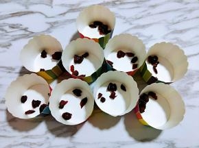 准备好纸杯首先放入蔓越莓干。拌好的蛋糕糊，细腻光滑，饱满，倒入纸杯中。