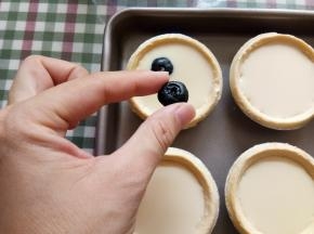 把混合液倒入塔皮八九分满，然后每个挞里面放入三四个洗净的蓝莓