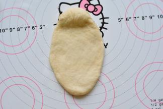 醒发好以后，进行擀卷，上面留一点，下面擀成椭圆型