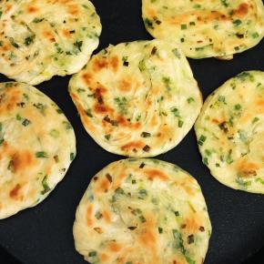 电饼铛烧热放油，把葱油饼坯放进去，记住煎的过程必须多翻两次面，翻面时最好再淋上少许油，用木铲多轻拍每一个葱油饼会更脆，香哦！两面金黄即可出锅哦！