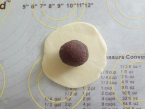 擀成中间厚边缘薄的皮放上豆沙同样用虎口向上收，