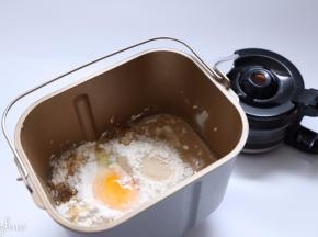 把中种食材一同放入面包桶。酵母在面粉中挖一个小坑放入。