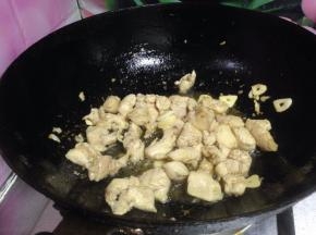 热锅凉油下入蒜片炒出香味。倒入鸡丁炒至变色