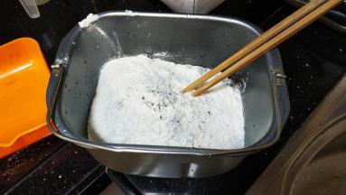 面包桶打入二个鸡蛋、水、盐、糖拌均匀，再倒入所有粉