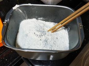 面包桶打入二个鸡蛋、水、盐、糖拌均匀，再倒入所有粉