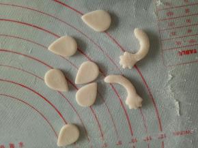 步骤3剩余的粉色面团揉一下，擀薄片，切出耳朵和胳膊的形状来(参考上一个小P猪菜谱)