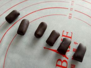 继续将黑色面团揉几下，搓成圆柱做猪小屁的腿，圆柱的粗细自己掌握就好，盖保鲜膜放冰箱