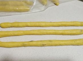 发好的面团三个一组，分别搓成细长的圆条。