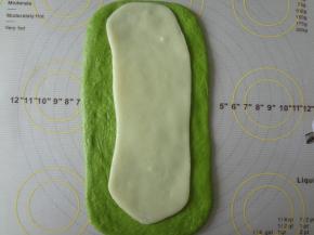 松弛好的面团擀开用手稍微整理成长方形，麻薯也擀成长方形放在面团上面