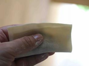 包裹馄饨：入15克以内馅，馅在中心向下位置呈长条形， 梯形馄饨皮短边上面沾水，馅在上，短边盖上入，未及长边1厘米处摁下使二片皮贴合，包四角元宝。