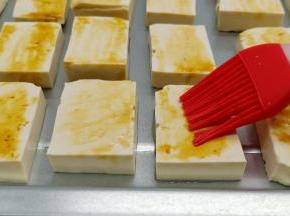 切片的豆腐依次码在烤盘上，刷一层加拿大芥花油，油味道清淡，适合烧烤，再刷一层生抽。