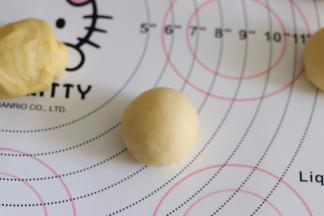 滚圆面团，方法是，用手扣住小面团，在揉面垫上转圈，可以用手掌部位的力度来滚圆，同时这也是再次排气过程。