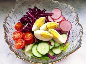 将切好的食材加入到装了生菜和苦菊的玻璃碗里。