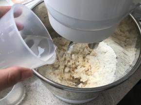 开动厨师机，缓慢加水，提前预留10克，根据面粉吸水程度增减