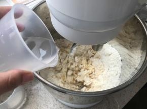 开动厨师机，缓慢加水，提前预留10克，根据面粉吸水程度增减