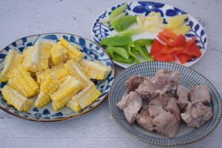 排骨洗净焯水捞出沥干水分备用，玉米洗净切成小段，青红椒去籽洗净切小块，蒜切片，姜切片，葱切寸段

