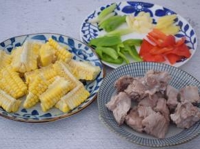 排骨洗净焯水捞出沥干水分备用，玉米洗净切成小段，青红椒去籽洗净切小块，蒜切片，姜切片，葱切寸段

